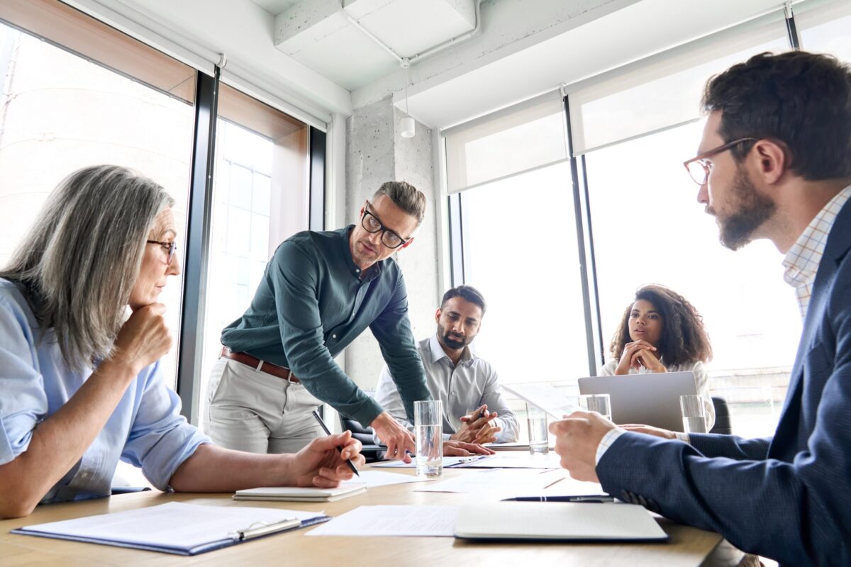 men and women in a business meeting, sitting around a table